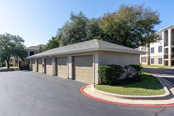 A building with a grey roof and a red circle on the ground in front of it.